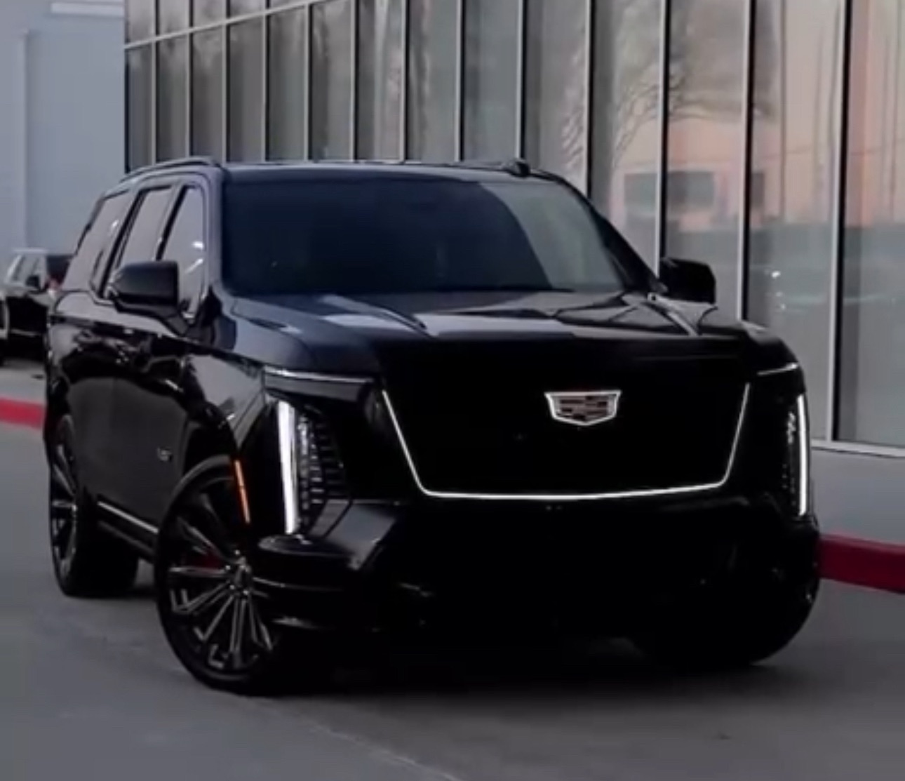 Black luxury SUV parked near glass building.